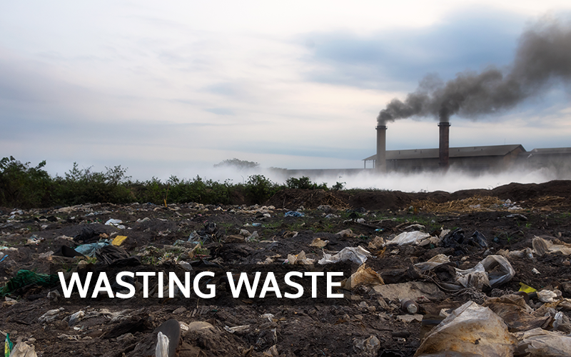 A photo of an open trash pit with an incinerator in the background